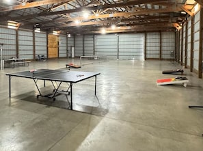 A spacious indoor area with a ping pong table, benches, and a table tennis table.