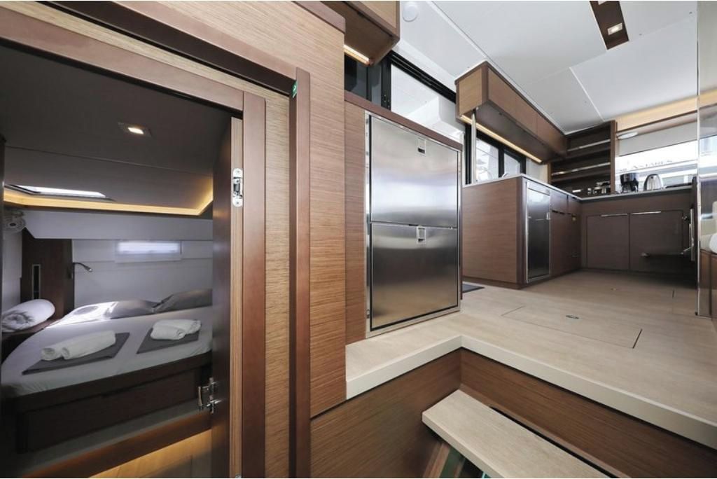 Un intérieur de camping-car compact et moderne, comprenant un coin cuisine, un lit et une salle de bain.