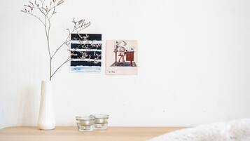 A room with a wooden desk, a white vase with a plant, and two framed pictures on the wall.