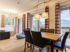 Ein Essbereich mit Holztisch und -stühlen, Karottenvorhängen und Blick ins Freie.