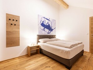 Ein Schlafzimmer mit einem Bett, einem Nachttisch, einer Holzvertäfelung und einem Wandbild.