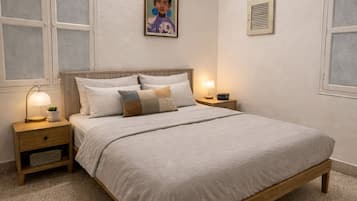 A bedroom with a bed, nightstands, a ceiling fan, and a wall-mounted air conditioning unit.