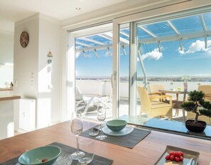 Ein Essbereich mit Tisch, Stühlen und Meerblick durch große Fenster.