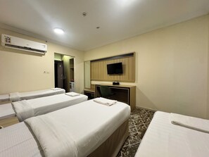 A hotel room with two single beds, a desk with a chair, a television mounted on the wall, and an air conditioning unit. - Tharawat Al-Andalusiyah Hotel (Makkah)