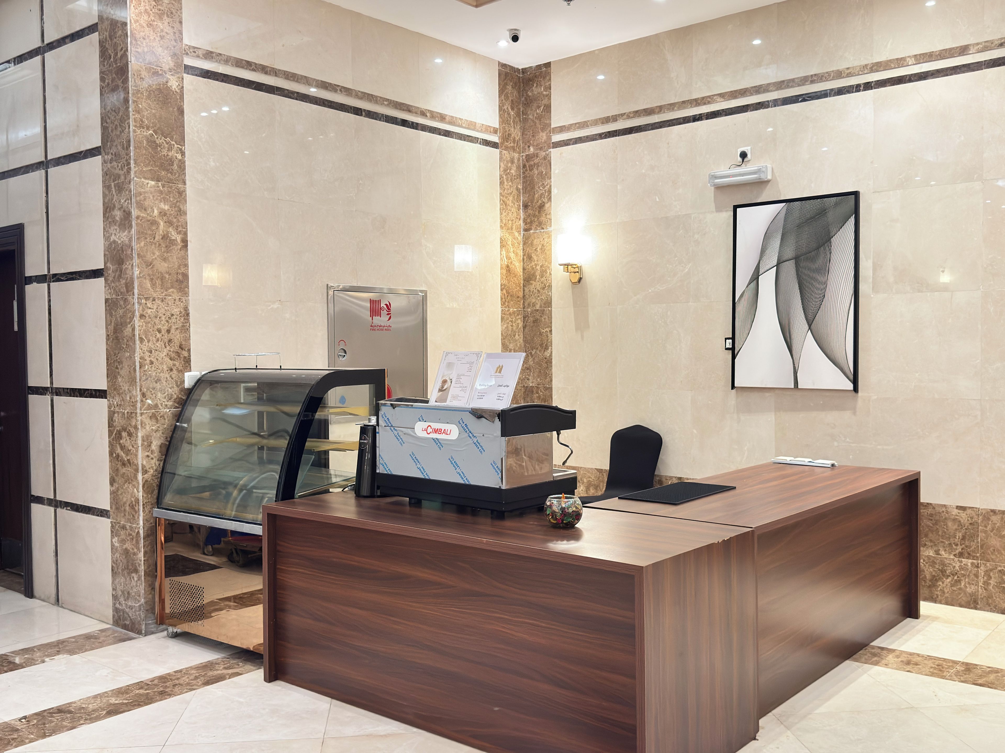 A reception desk with a glass partition, a water dispenser, and a menu stand.