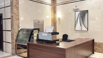 A reception desk with a glass partition, a water dispenser, and a menu stand.