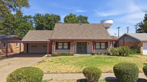 A single-story house with a covered porch, a garage, and a water tank on the roof. - Glenridge Getaway - 3BR/2BA - Centrally Located (Lubbock)