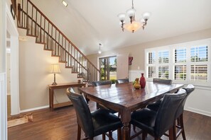 A spacious dining area with a large wooden table and leather chairs, a staircase with wooden railings, and a chandelier. - Glenridge Getaway - 3BR/2BA - Centrally Located (Lubbock)