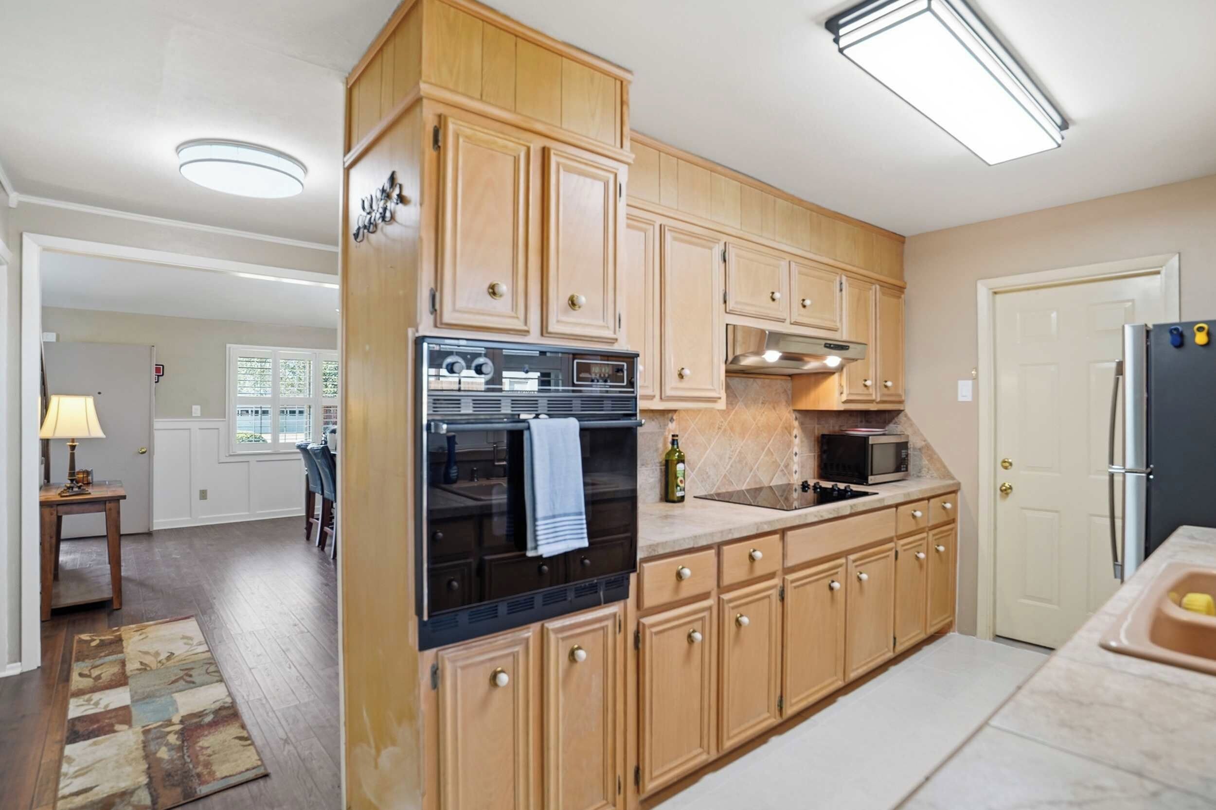 A kitchen with wooden cabinets, a refrigerator, an oven, a microwave, and a sink.