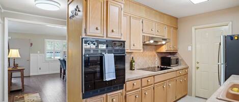 A kitchen with wooden cabinets, a refrigerator, an oven, a microwave, and a sink.