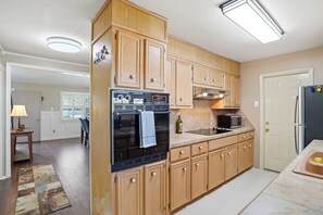 A kitchen with wooden cabinets, a refrigerator, an oven, a microwave, and a sink. - Glenridge Getaway - 3BR/2BA - Centrally Located (Lubbock)
