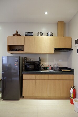 Eine moderne Küche mit Holzschränken, einem Edelstahlkühlschrank, einer Mikrowelle und einem eingebauten Backofen.