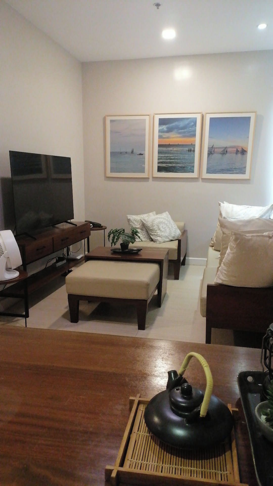 Una sala de estar con televisor de pantalla plana, un sofá, una mesa de centro y un adorno sobre la mesa.