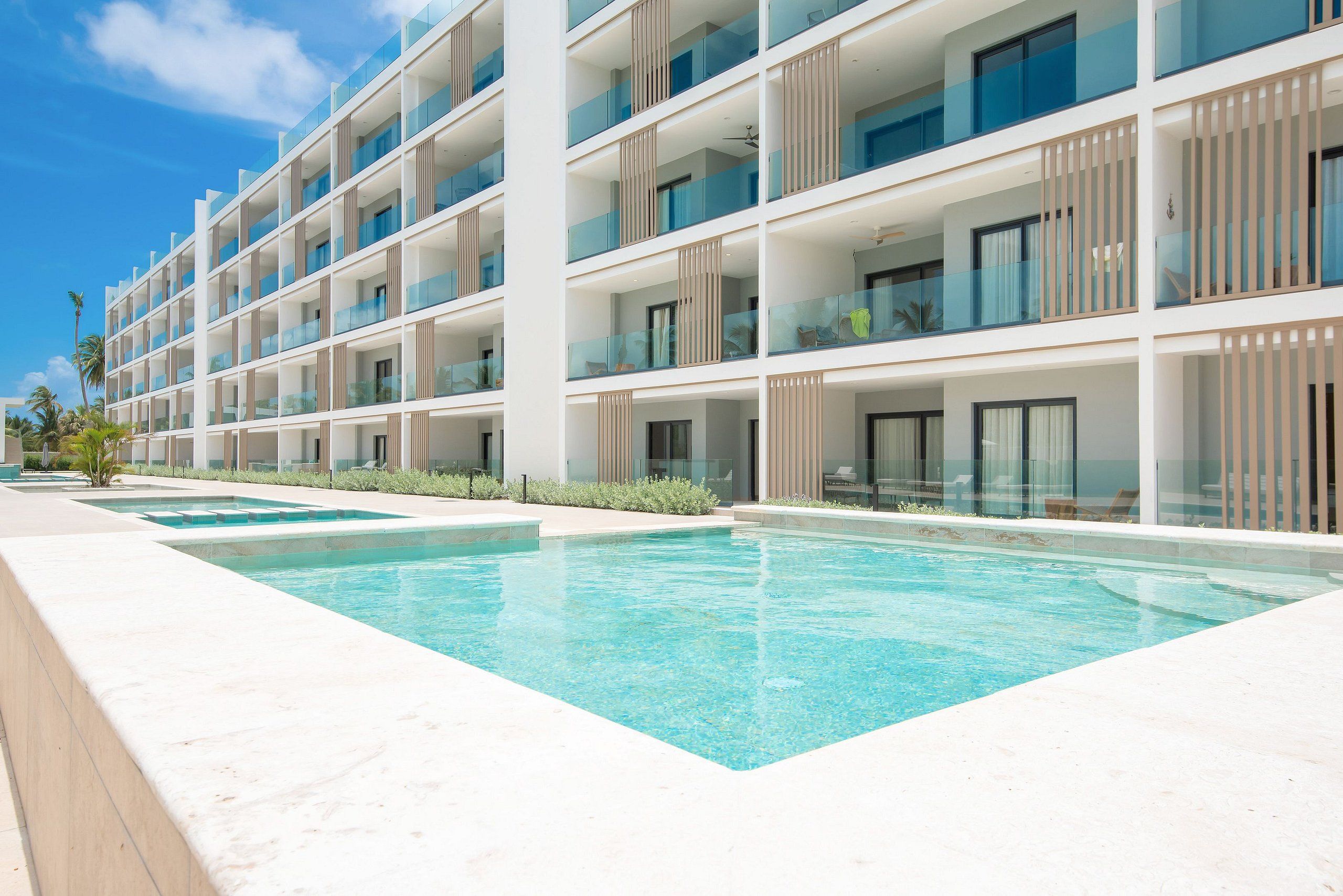 A multi-story hotel with a swimming pool and outdoor seating.