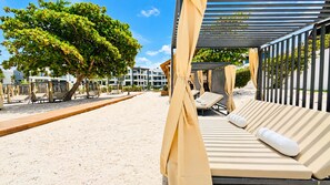Eine Strandlounge mit Liegestühlen, einer Holzterrasse und einer überdachten Sitzgelegenheit.
