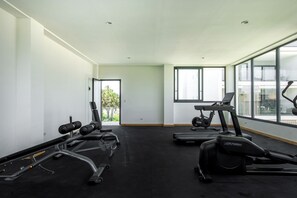 Ein Fitnessstudio mit Cardiogeräten, Krafttrainingsgeräten und großen Fenstern.