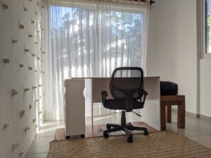 A room with a desk, office chair, and a suitcase on a wooden stool. - Casa Natik - A Mayan House in the Jungle. Ideal for families and ecotourism (Chemuyil (jungle))