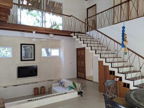 A multi-level interior with a staircase, seating area, and a flat-screen TV. - Casa Natik - A Mayan House in the Jungle. Ideal for families and ecotourism (Chemuyil (jungle))