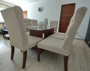A dining area with a glass-top table and cushioned chairs. - Acapulco Diamante / Jacuzzi / Club de Playa (Acapulco de Juárez)