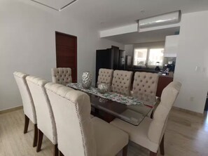 A dining area with a glass-top table and six upholstered chairs. - Acapulco Diamante / Jacuzzi / Club de Playa (Acapulco de Juárez)