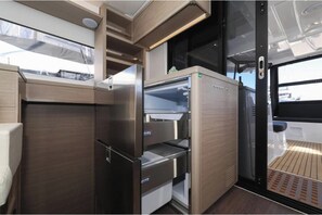 A compact kitchen with a built-in refrigerator, a microwave, and a sink. - Lagoon 46 - NUVOLA (Bibinje)