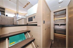 A compact, modern interior with a bed, built-in storage, and a small seating area. - Lagoon 46 - HASTA LA VISTA (Bibinje)