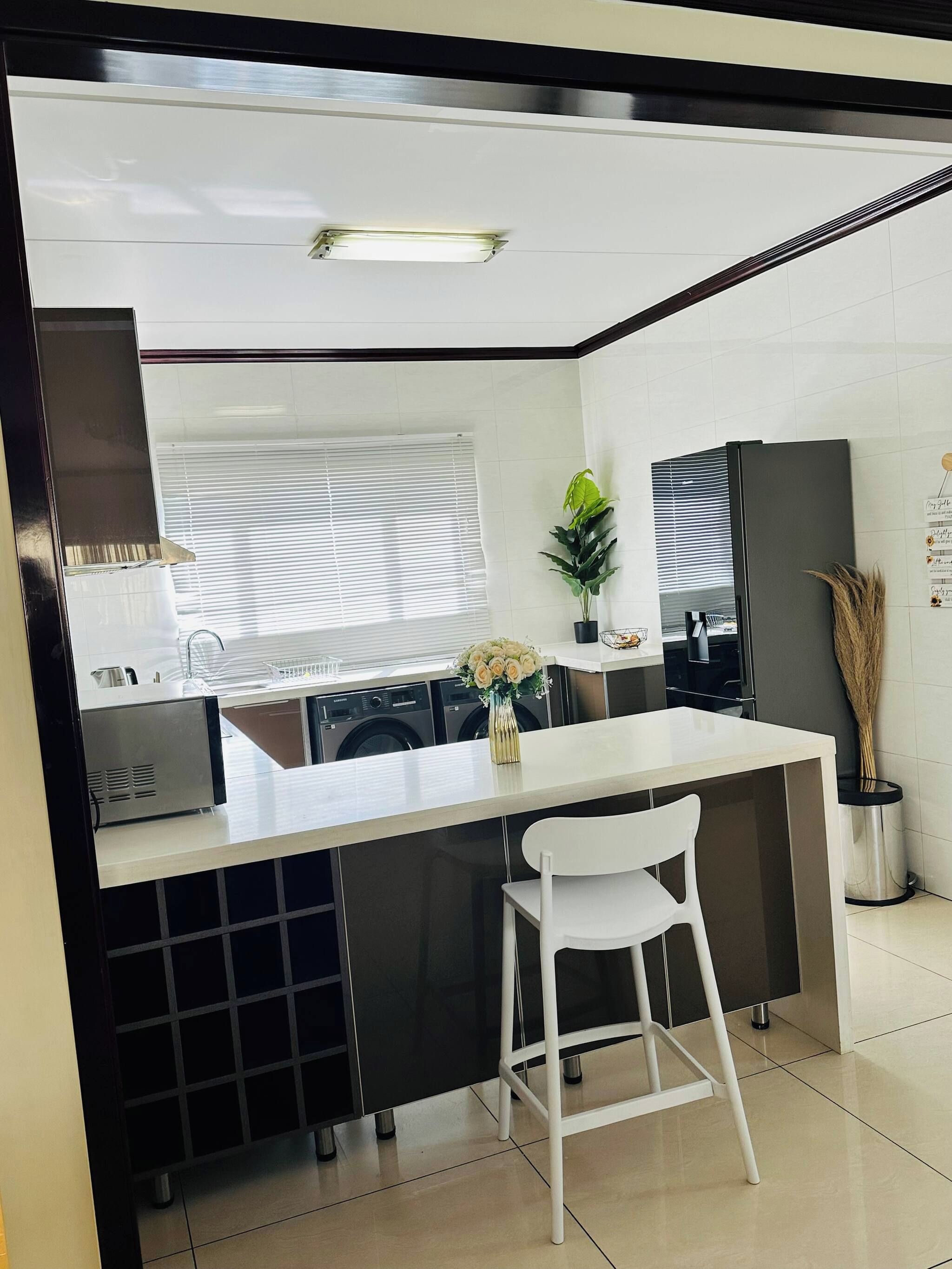 A compact kitchen with a central island, a washing machine, and a refrigerator.