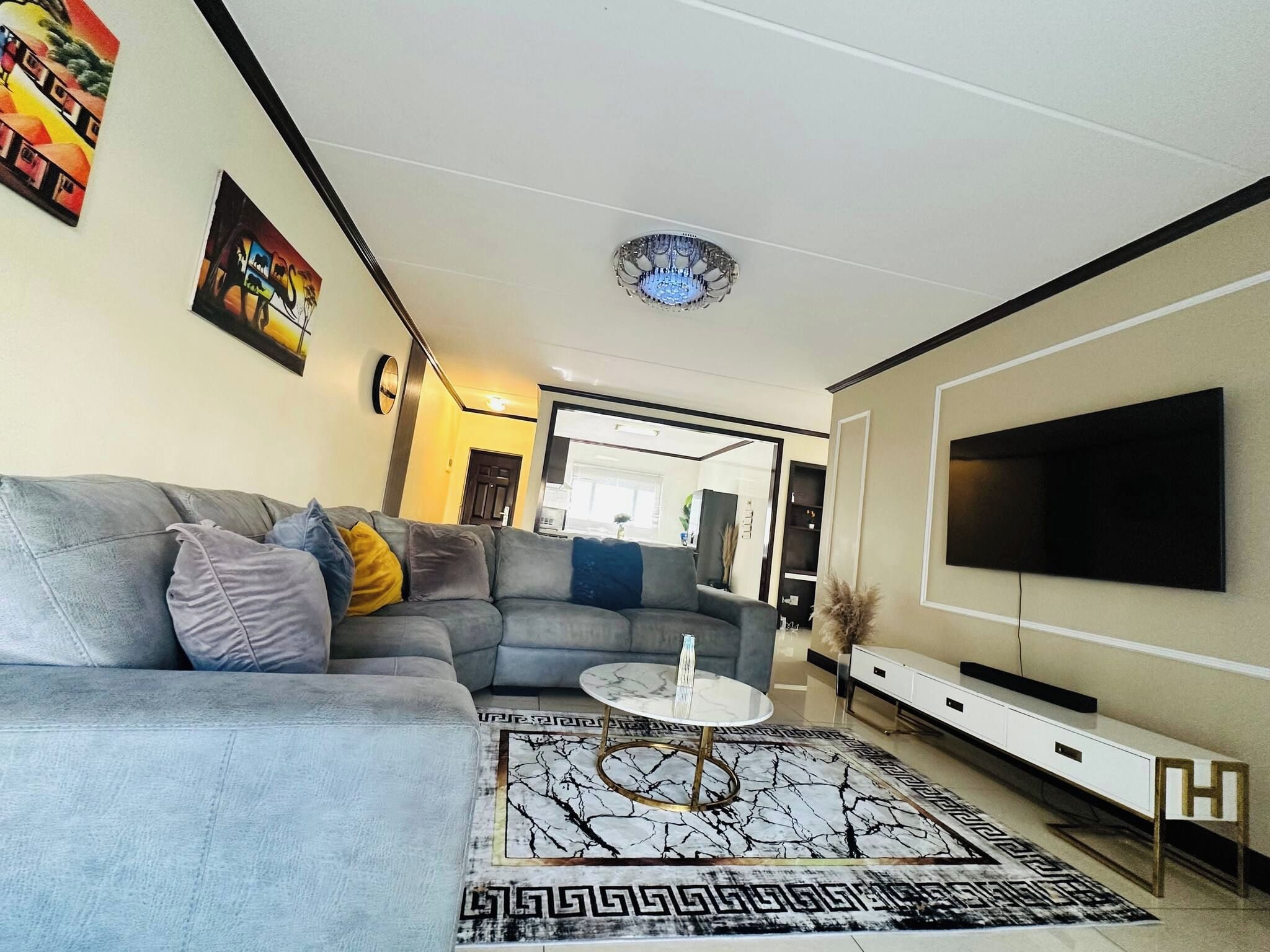 Ett modernt vardagsrum med en grå soffa, ett soffbord i marmor och en platt-TV som är monterad på väggen.