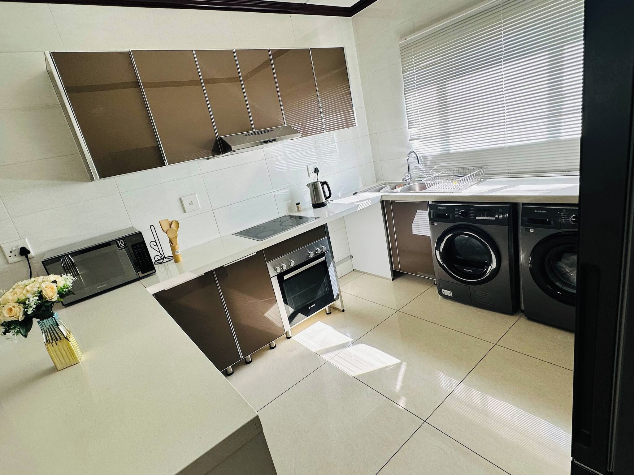A modern kitchen with a built-in oven, microwave, and washing machine.