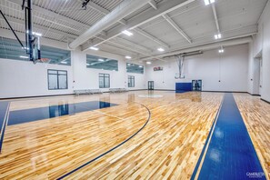 An indoor basketball court with a wooden floor, basketball hoops, and seating areas.