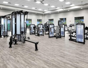 A gym with various exercise machines, a bench, and large windows. - 4-bedroom house in beautiful Estero. Pools, Gym. Tennis. Pickleball. Beaches. (Estero)