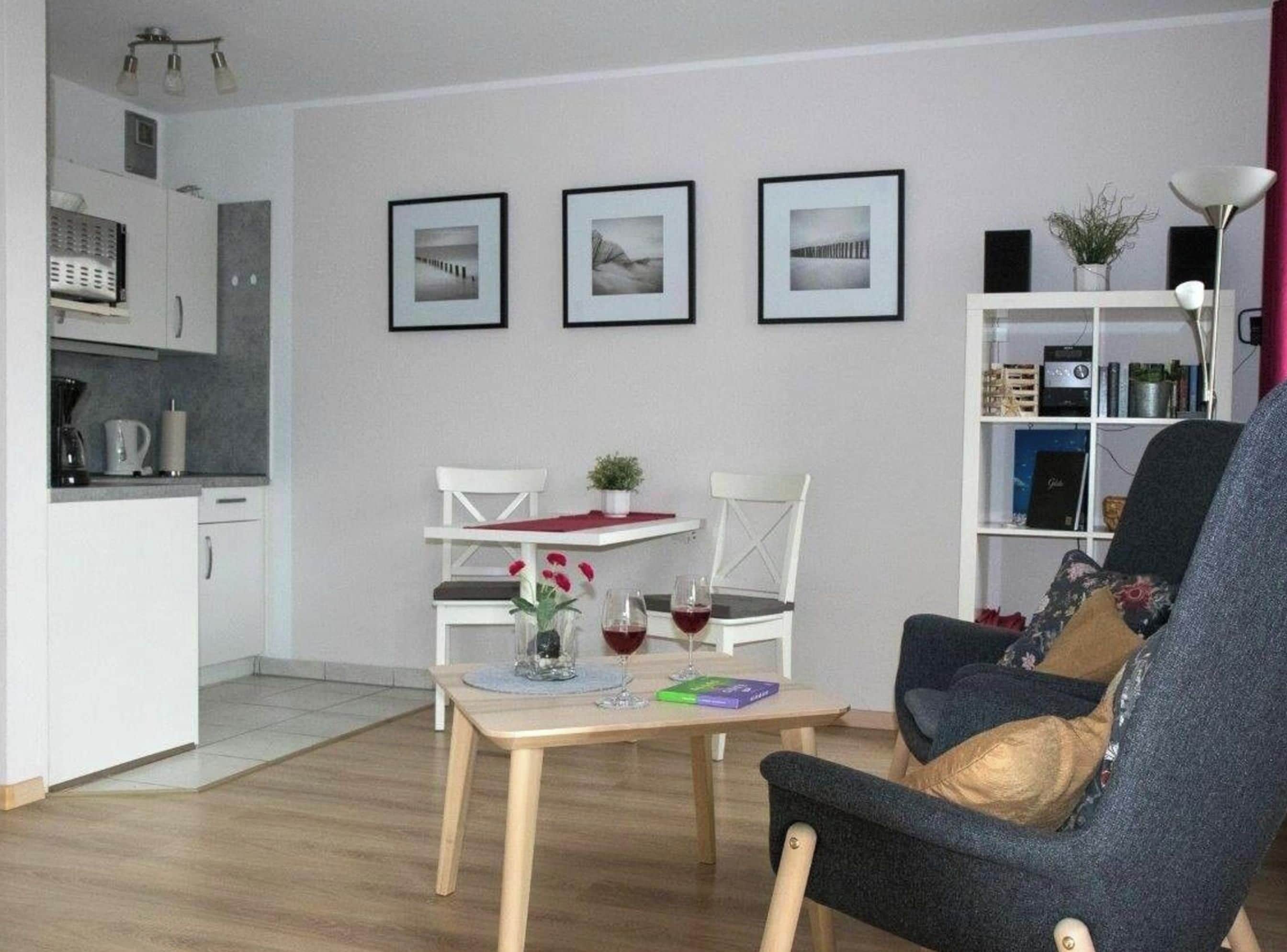 Een woonkamer met een eettafel, twee stoelen, een bank en een boekenkast.