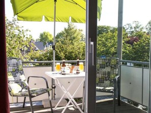 Ein Balkon mit Tisch, Stühlen und einem grünen Sonnenschirm.