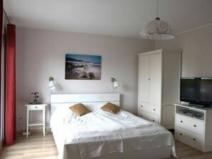 A bedroom with a bed, bedside tables, a wardrobe, a television, and a painting on the wall. - Studio 11 on the 1st Floor of Haus Stranddistel (Zingst)