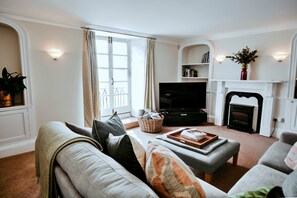 Una sala de estar con sofá, televisión, chimenea y estantería.