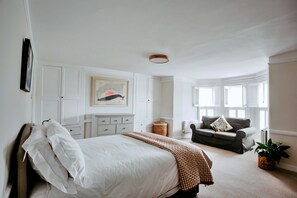Un dormitorio con cama, cómoda, silla y ventana con persianas.