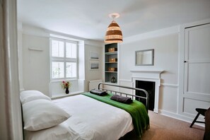 Ein Schlafzimmer mit Bett, Fenster, Kamin und einer Hängelampe.