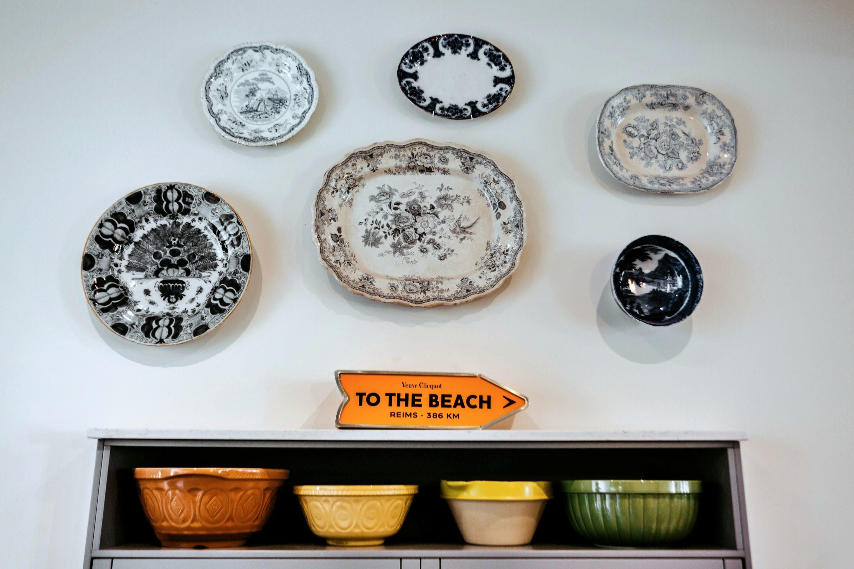 Una colección de platos decorativos y un letrero señalizador en una pared.