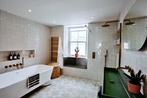 Un baño moderno con una bañera independiente, zona de ducha y ventana con vistas.