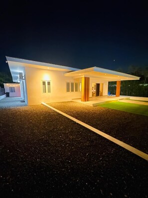 Una casa moderna con porche cubierto y un camino de entrada bien iluminado.