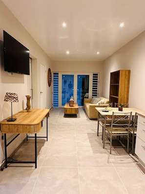 Una sala de estar moderna con un televisor de pantalla plana, una mesa de comedor de madera, un sofá y una mesa baja.