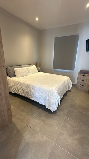 Un dormitorio con cama, mesita de noche, cómoda y ventana.