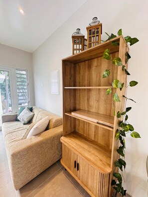 A wooden cabinet with shelves and a door, accompanied by a sofa and a window. - Serene 5-bedroom house with AC in charming Willemstad (Willemstad)