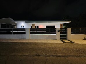A modern house with a gated entrance, a driveway, and a well-lit exterior. - Serene 5-bedroom house with AC in charming Willemstad (Willemstad)
