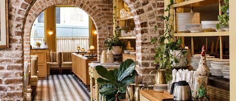 A restaurant with brick walls, checkered flooring, and hanging pendant lights.
