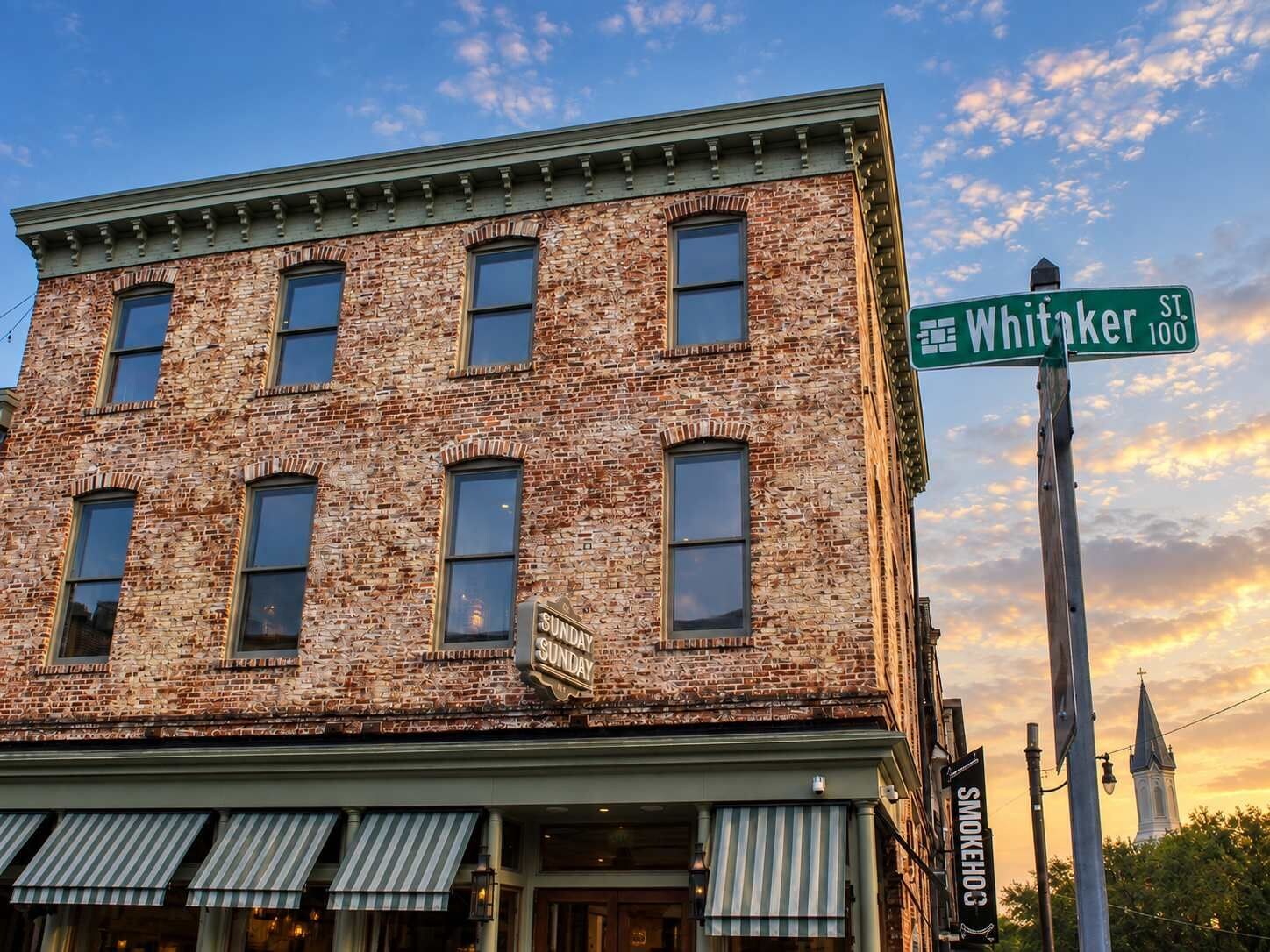 A brick building with a green street sign for Whitaker St.