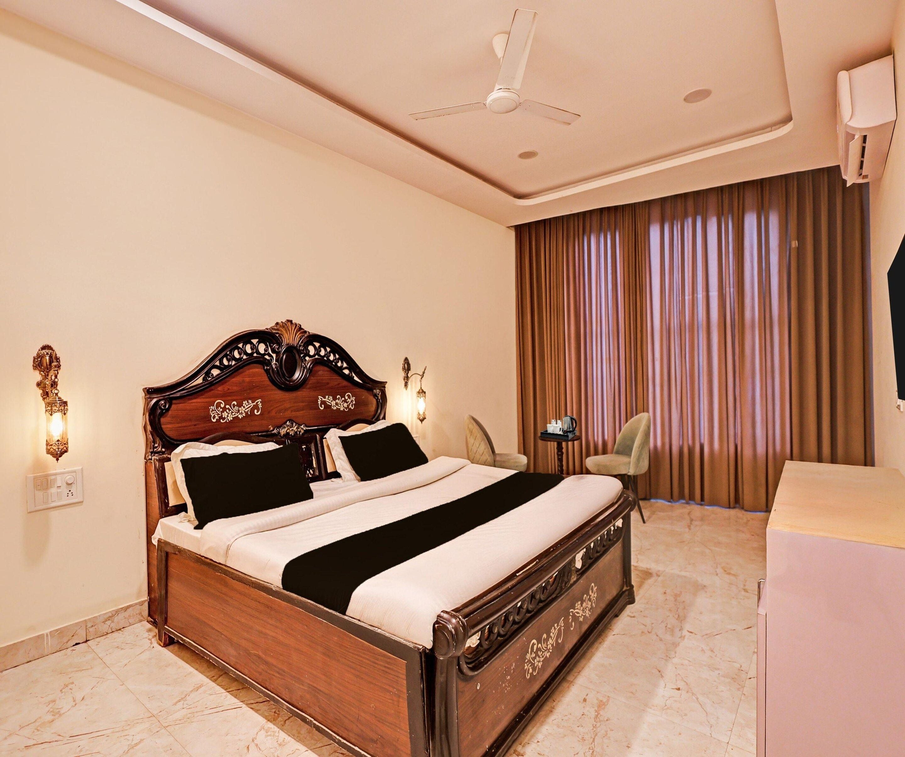 A hotel room with a large bed, a ceiling fan, a desk, and a chair.
