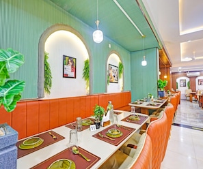 A restaurant with booths, tables, and a green-striped wall. - Deluxe Room Hotel U Turn & Restaurant (Dr. Ambedkar Nagar)