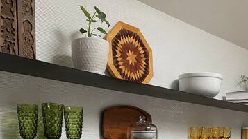 Une étagère ornée de divers objets décoratifs, notamment une plante, un objet en bois aux motifs géométriques et différents articles en verre.