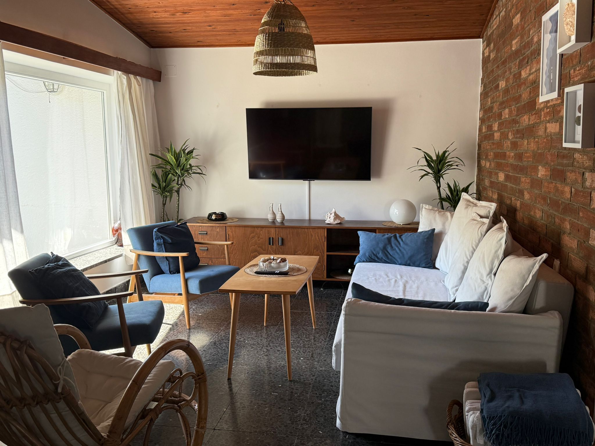Una sala de estar con televisor de pantalla plana, un sofá, una mesa de centro y dos sillones.